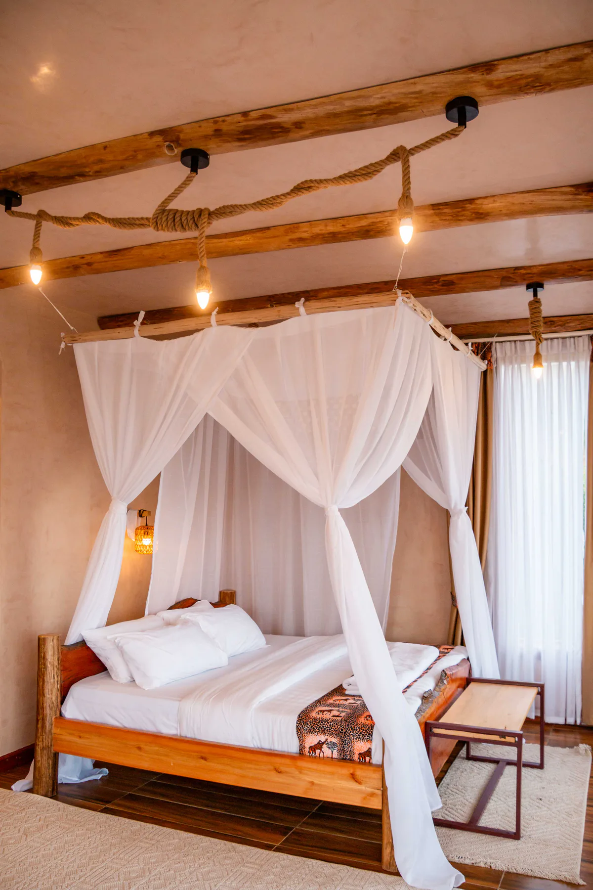 Guest room with a timber bed, mosquito net and handcrafted rope lighting