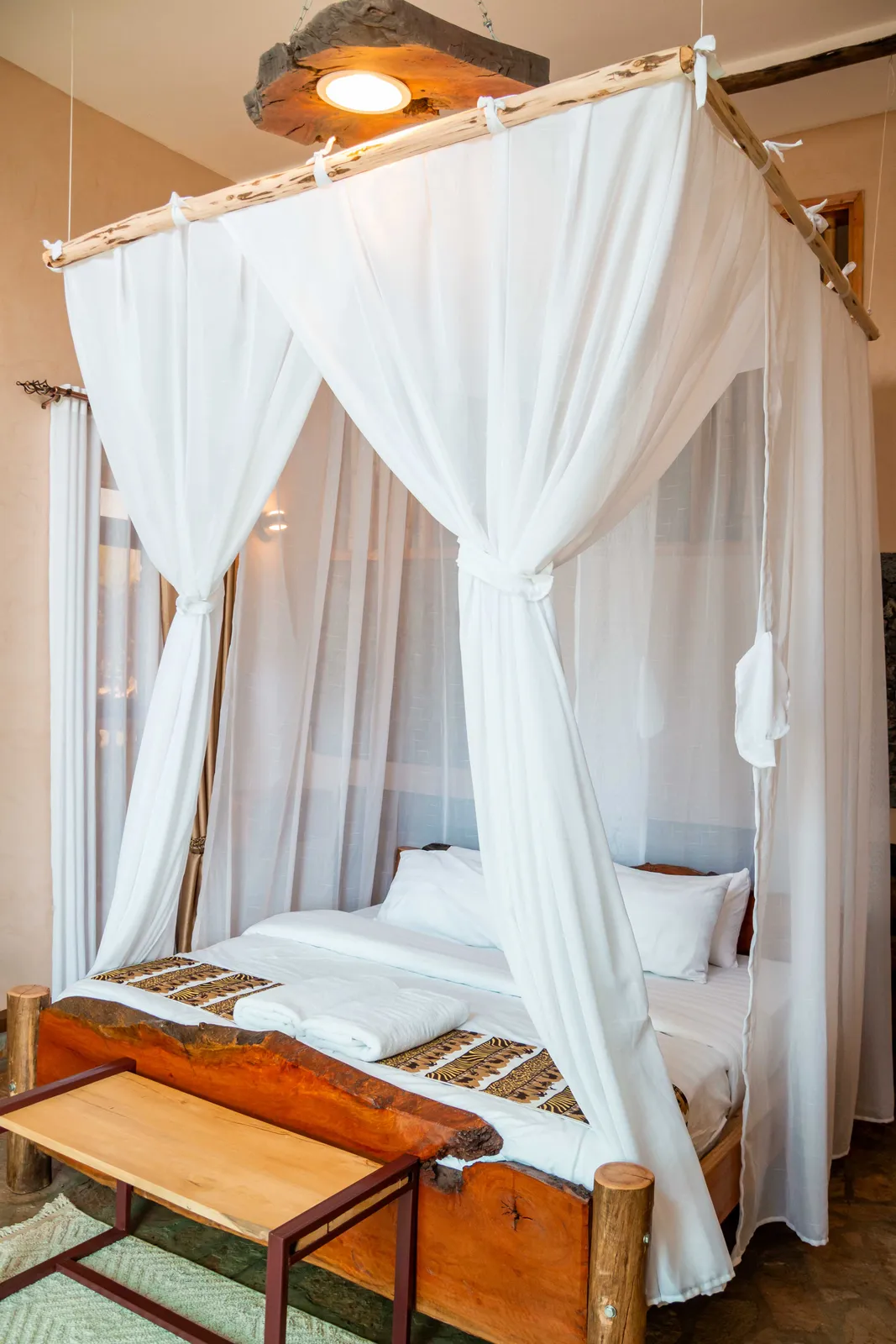 Guest room detail with a timber canopy bed and soft white mosquito net